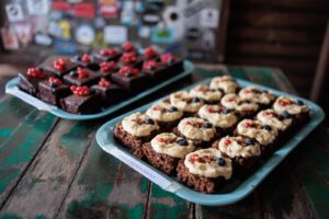 vegane brownies mit obst garnitur auf zwei blauen Tabletts serviert